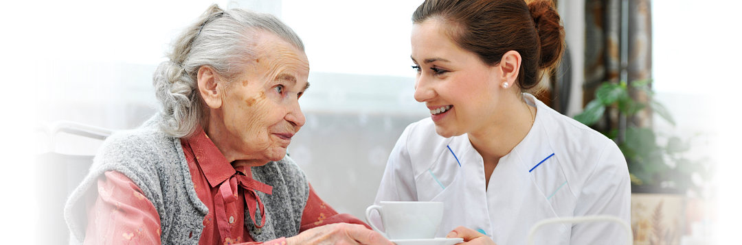 caregiver handling a cup of tea for elderly woman